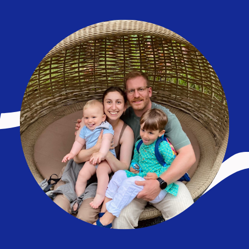 Josh sits with his wife and two sons on a weaved basket.