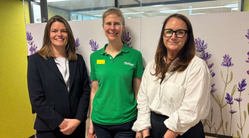 Three women stand smiling.