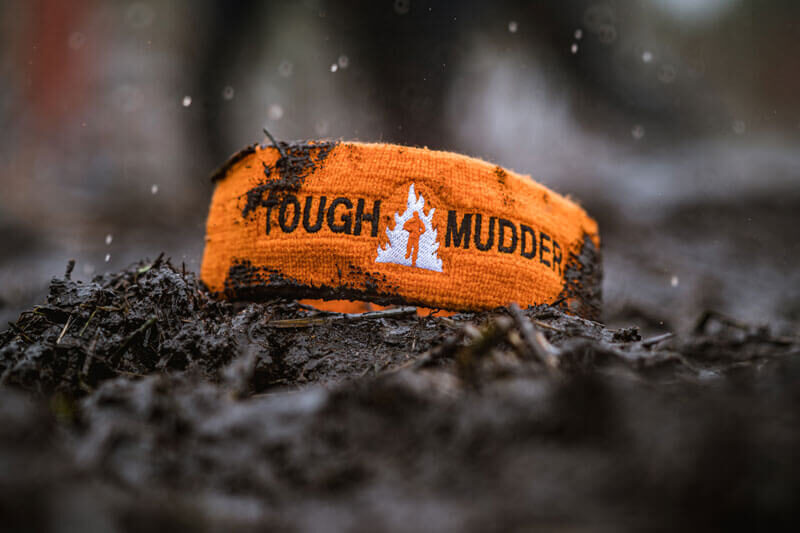 Orange Tough Mudder headband in mud