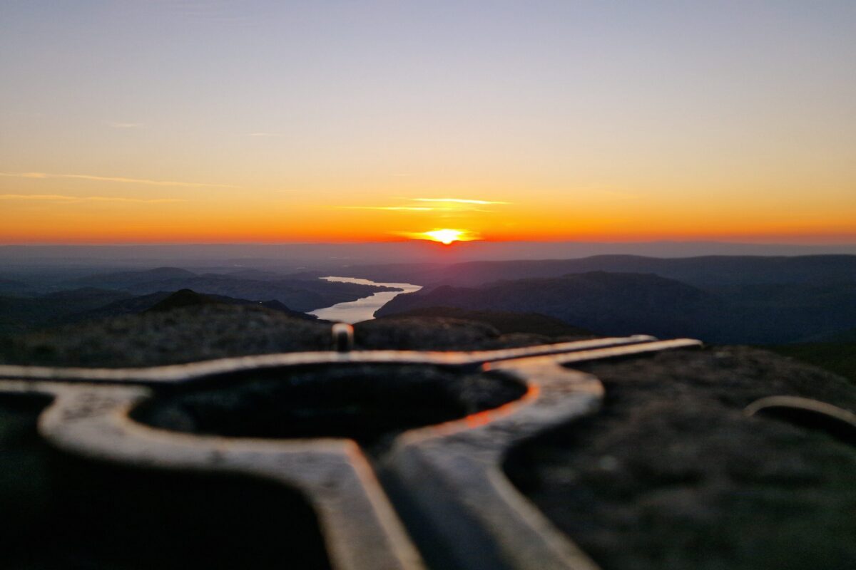 Sunrises over Red Tarn with a Trig Point in the foreground